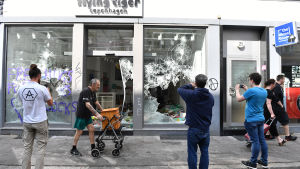 Några personer fotograferar en affär som vandaliserats under G20-protesterna. Några personer fotograferar en affär som förstörts under G20-protesterna.