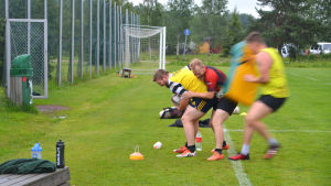 Hit med bollen! rugbyspelare på plan. En man i rött försöker ta bollen bakifrån av en man i gult.
