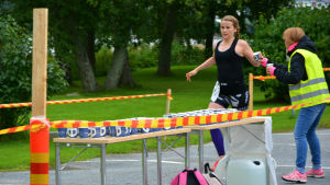 Triatlon avslutas med löpning. Triathleten Heidi Granholm tar emot en mugg vatten av en funktionär när hon springer