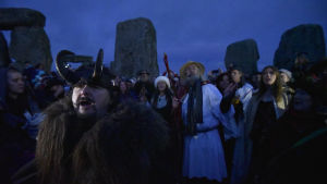 Människor firar vintersolståndet vid Stonehenge. I förgrunden en man med en behornad hjälm på huvudet.