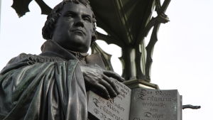 Staty av Martin Luther med nya testamentet på tyska Staty i Wittenberg föreställandes Martin Luther med Nya testamentet skriven på tyska uppslaget i sina händer