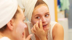 Att använda exfolierande produkter är bra för att få bort döda hudceller. Kvinna applicerar ansiktsmask.