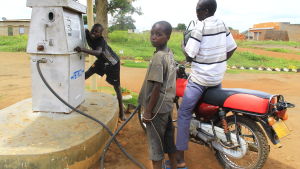 Många barn går inte i skola. De här pojkarna arbetar vid en handdriven bensinpump i Pajule. barn arbetar vid en handdriven bensinpump i norra uganda