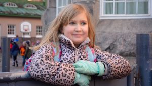 Amelie Lagerström tycker att det är tråkigt om skolan stängs. Åttaårig flicka lutar sig mot en metallport