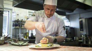 Viktor Ovtsinnikov har tidigare jobbat bland annat i Åbolands skärgård och i Lappland. Han hälsar på familjen i Estland ungefär var fjärde vecka. Kocken Viktor Ovtsinnikov strör örter över en vacker matportion.