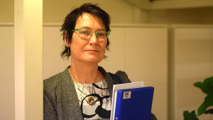 Kukka-Maaria Lukkonen fick svara på frågor från oroliga ledamöter om Roxx framtid. En kvinna med kort mörkt hår och gröna glasögonbågar håller i en bunt papper. Hon heter Kukka-Maaria Luukkonen.