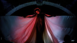 Loie Fuller (Soko) dansar iklädd en enorm sidendress som belyses bakifrån med röda lampor.