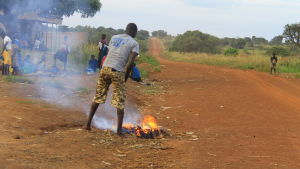 En man bränner skräp vid gatan på väg mot Pajule. man bränner skräp i norra uganda