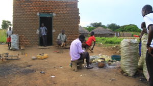 Folk rostar majs och umgås i byn Lanyatidos centrum. Här finns inte mycket att göra. bycentrum i norra uganda