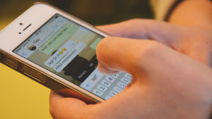 En närbild av händer som skriver meddelandet vgd på appen whatsapp på en smarttelefon.