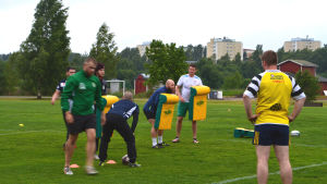 Snart kraschar lagkamrater in i de gula dynorna. rugbyspelare på gräsplan håller upp gula dynor