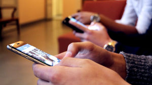 Det är lätt hänt att man sätter sig ner med mobilen i stället för att göra någon fysisk aktivitet En närbild på ungdomar som surfar på sina smarttelefoner.