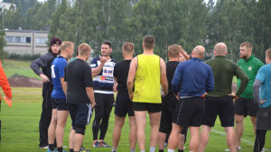 Casey Dent i mörkblått och vitt samlar ihop de andra spelarna i en klunga inför nästa övning. Casey dent i blått och vitt samlar ihop de andra spelarna i en klunga.