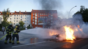 Brandmän i Hamburg släcker en brinnande bil som fattat eld i samband med demonstrationerna i Hamburg inför G20. Brandmän i Hamburg släcker en brinnande bil som fattat eld i samband med demonstrationerna i Hamburg inför G20-mötet.
