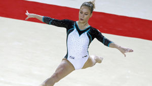 Gymnastik blir en dyr hobby då man börjar tävla. På bilden Rysslands Ksenia Afanasjeva under en tävling 2015. Gymnasten Ksenia Afanasjeva gör spagat klädd i dräkt med vitt, turkost och svart.