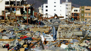 En kvinna letar efter sina ägodelar bland bråtet i tsunamidrabbade Onagawa den första april 2011.