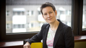 Anna Moring anser att utbudet av barnkultur som tar upp regnbågsperspektiv har blivit bättre. Porträtt av Anna Moring framför ett fönster klädd i kavaj och t-skjorta.