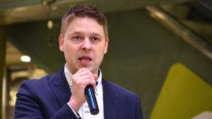Mika Sivula: Lojo ska bli Finlands mest invånarvänliga kommun. En medelåldedersman i vit skjorta och blå kavaj, han pratar med mikrofon i handen.