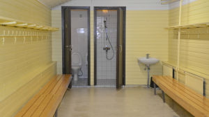 Vattnet kan ha stått länge i rören i sådana lokaliteter som inte använts på väldigt länge, till exempel omklädningsrum. Arkivbild. Ett omklädningsrum som är i ganska dåligt skick. Väggarna är citrongula och det finns träbänkar på sidorna.