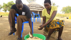 Francis och hans syster Irene hjälps åt att sprita majs. kvinna och man spritar majs i norra uganda
