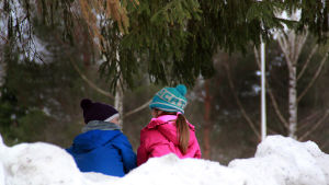 Ensambarn knyter ofta djupa vänskapsband. Två barn sitter i en snödrivar och pratar.