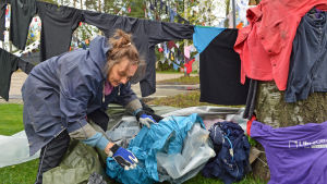 Konstnären Kaarina Kaikkonen sätter den sista touchen på sitt konstverk ... Konstnären Kaarina Kaikkonen rotar efter nästa plagg att hänga upp.