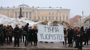 Både personal och studenter slöt upp under onsdagens ljusdemonstration vid HU. Banderoll med texten Tyhmä yliopisto