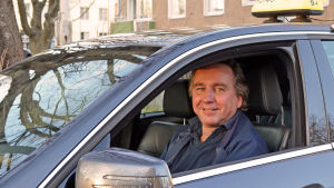 Kaj Rönnholm är taxiföretagare och vice ordförande för Helsingin Taxiautoilijat ry. Taxichauffören Kaj Rönnholm tittar ut genom fönstret i sin taxi