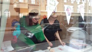 Att få arbeta på samma ställe ibland är viktigt för Jolin Slotte och Pauliina Pesonen. Här på galleri Kalleria i Berghäll. Jolin Slotte och Pauliina Pesonen genom skyltfönstret till Galleri Kalleria.
