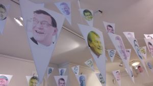 Bekanta ansikten och teman gör att utställningen lockar många som inte känner till projektet sedan tidigare. Girlander med vimplar i galleritaket.