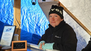 Tanja Åkerfelt Tanja åkerfelt har svarta friluftskläder och ljusblåa fingerlösa fingervantar, "torgvantar".
