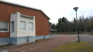 Aleksis Kiven koulu är en av de skolor som har problem med inomhusluften. Det klarnar först i nästa år hur mycket det kostar att åtgärda problemen. En skolbyggnad i rött tegel och en tom skolgård.