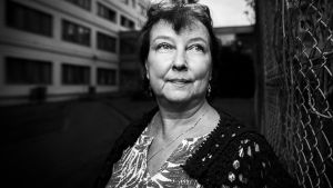 Nainen, Leena Virtanen, poseeraa kameralle verkkoaidan vieressä,