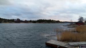 Vågskvalp eller stormigt hav? Kan det ha en lugnande effekt på vandrare? solen tittar fram över öar i skärgården, men det är mörka moln och stormigt väder i november.
