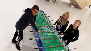 Tommy Weckström, Pernilla Tackman och Ellen Sillman i korridoren på den svenska sidan av Nickby hjärta. Tommy Weckström Pernilla Tackman och Ellen Sillman står vid ett av spelborden i skolcentret Nickby hjärta i Sibbo