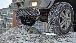 Parkering a la Degerman. Närbild på terrängbil där däcken är uppkörda på en snöhög.