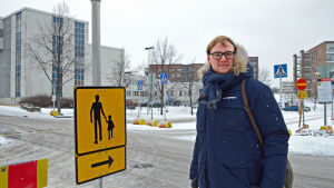 Niklas Aalto-Setälä är cykelkoordinator i Helsingfors. Nikas Aalto-Setälä poserar framför en gul skylt som dirigerar om forgängartrafiken.