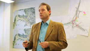 Hannu Lehtikankare, byggchef på Esbo stad. Bakom honom ser man tunnelplanerna som nu förverkligas. Byggchef Hannu Lehtikankare, Esbo stad, framför planerna på Kägeluddentunneln