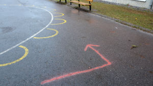 Pilarna visar var banan går. en pil har målats på skolgården för att barnen ska kunna springa maraton