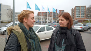 My Ström och Mette Strauss. My Ström och Mette Strauss på parkeringsplats, med Yle-flaggor i bakgrunden.