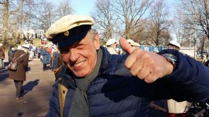 Benny Törnroos önskar alla en glad första maj. Benny Törnroos gör tummen upp i studentmössa i Kajsaniemiparken.