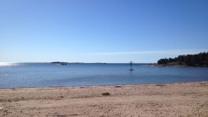 Plagen. Sandstrand i Hangö med blått vatten och blå himmel. Stranden heter Plagen.