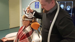 Läkaren Aleksi Sihvonen stimulerar forskaren Sini Hämäläinens hjärna, för att visa hur magnetisk stimulering av hjärnan fungerar. Sini Hämäläinen och Aleksi Sihvonen