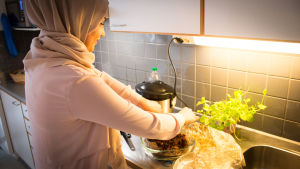 Saif on yleensä perheen kokki, mutta tällä kertaa täytetyn kanan on valmistanut Hajar - Saifin ohjeilla. huivipäinen laittaa keittiössä ruokaa