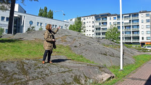 Professor Laura Kolbe pekar ut detaljer i fasaden. Laura Kolbe står på en bergsknall och pekar på ett höghus.