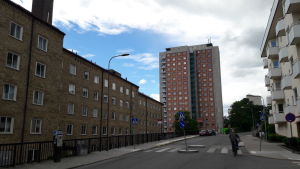 Ett rum i en studentkorridor här kan ta ett halvt år att få, i bästa fall. Genomsnittet är en väntetid på tre år för en studentbostad. Högt hus med studentbostäder i rödtegel i ändan av gatan. lägre hus med bostäder invid.