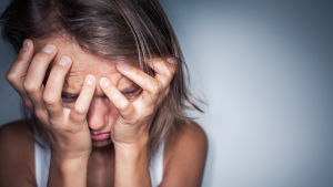 Hur låter din inre röst när du känner dig stressad? En flicka som har ansiktet i händerna.