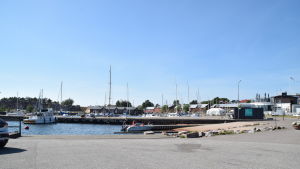 Östra hamnen är turisternas samlingsplats. Hamn med motor och segelbåtar. Blå himmel syns i bakgrunden och röda byggnader.