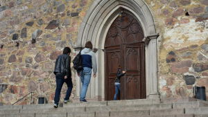 Människor på väg till kvällsmässan i Åbo domkyrka. Människor går uppför trapporna till Åbo domkyrka.