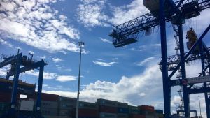 Lyftkranar i containerterminalen i Gdansk mot en molnig och solig himmel.